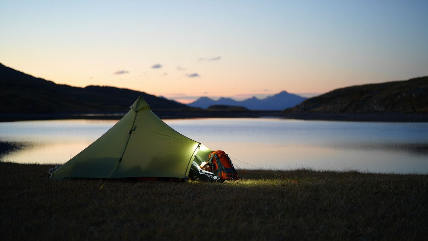 Tente de bivouac au crépuscule près d'un lac de montagne