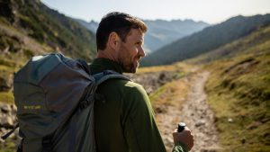 Randonneur observant un sentier de montagne avec relief visible sans texte ni marque